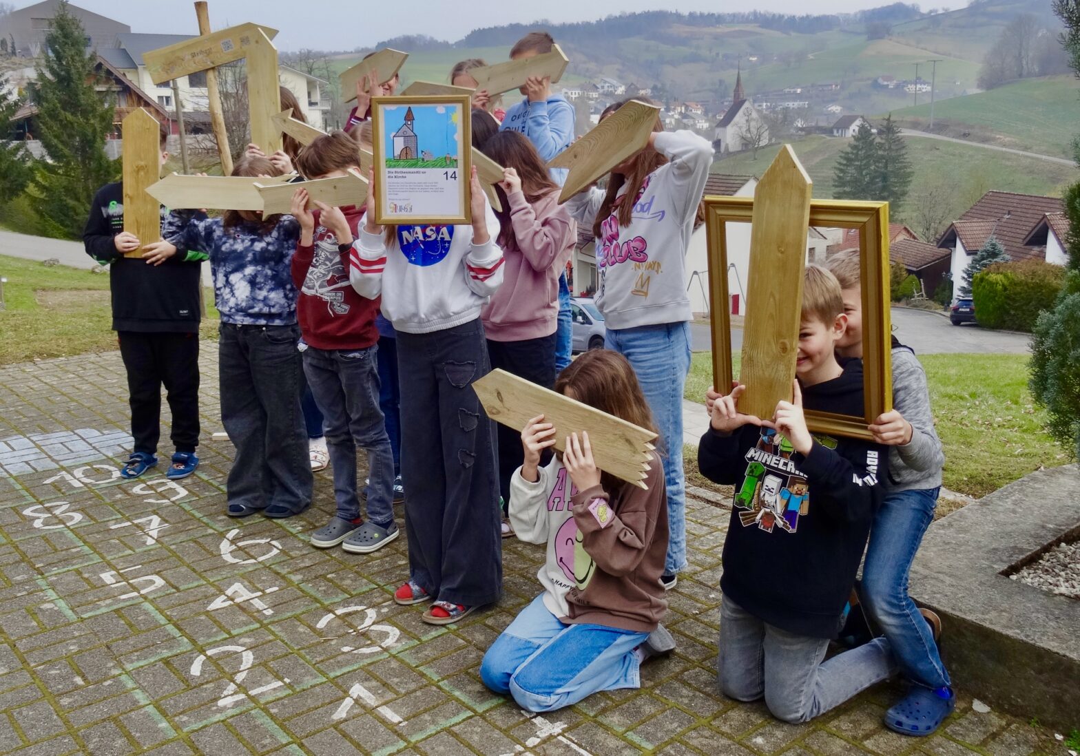 Kinder halten Wegweiser aus Holz vor ihre Gesichter.