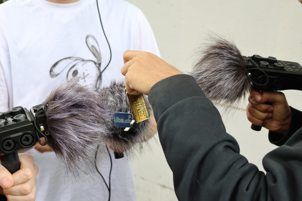 Drei Hände halten Soundaufnahmegeräte und nehmen den Klang eines Schlüssel mit Anhänger auf.