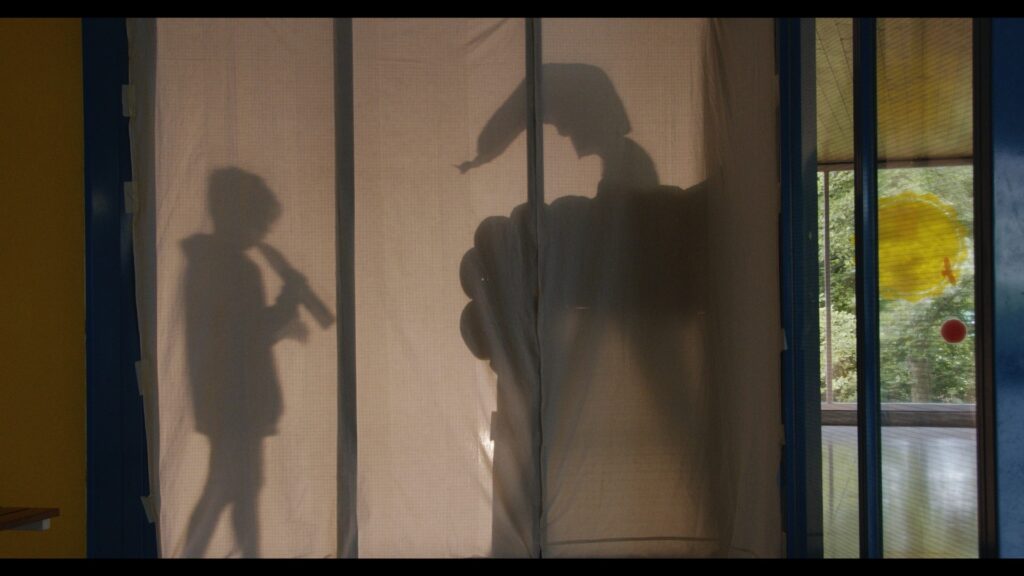 Schatten vonvzwei Kinder hinter einem Vorhang, eines davon spielt Flöte